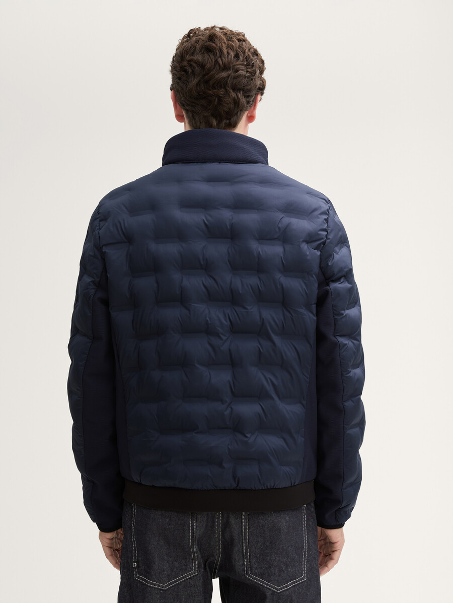 chaqueta acolchada ligera híbrida con capucha y cuello alto.